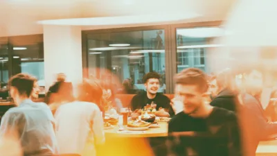Grupa studentów spożywa niedrogie posiłki w przytulnej warszawskiej restauracji, ciesząc się jedzeniem i atmosferą przy wspólnym stole