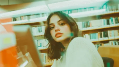 Studentka pracująca nad przypisami w pracy naukowej, używająca terminu ibidem w tekście. Na biurku widoczne są podręczniki akademickie i laptop z programem do edycji tekstu.