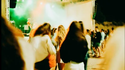 Studenci bawiący się podczas Juwenaliów Uniwersytetu Warszawskiego 2025, koncert wieczorny z kolorowymi światłami scenicznymi