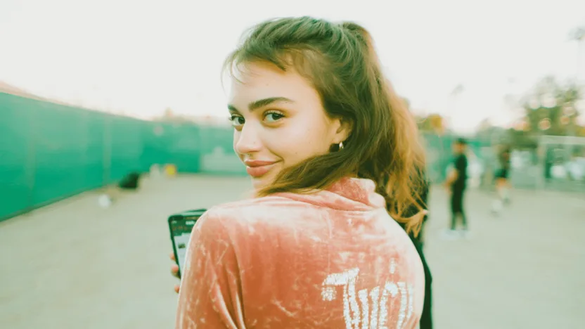 juicy couture - studentka w różowym welurowym dresie Juicy Couture pokazująca zniżkę studencką na telefonie