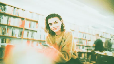 gandalf kod rabatowy - studentka pokazująca na telefonie kod zniżkowy do księgarni internetowej w bibliotece uniwersyteckiej