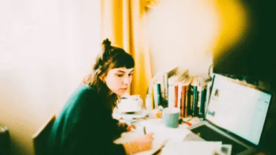 Wstęp do pracy magisterskiej - studentka pisze wstęp do pracy magisterskiej przy laptopie w bibliotece