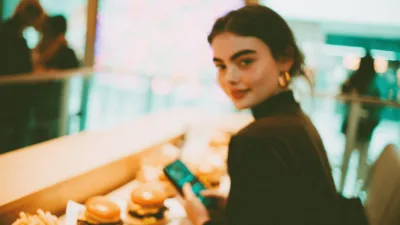 Max Premium Burgers kupony - studentka pokazująca na telefonie kod rabatowy MAX Premium Burgers w restauracji